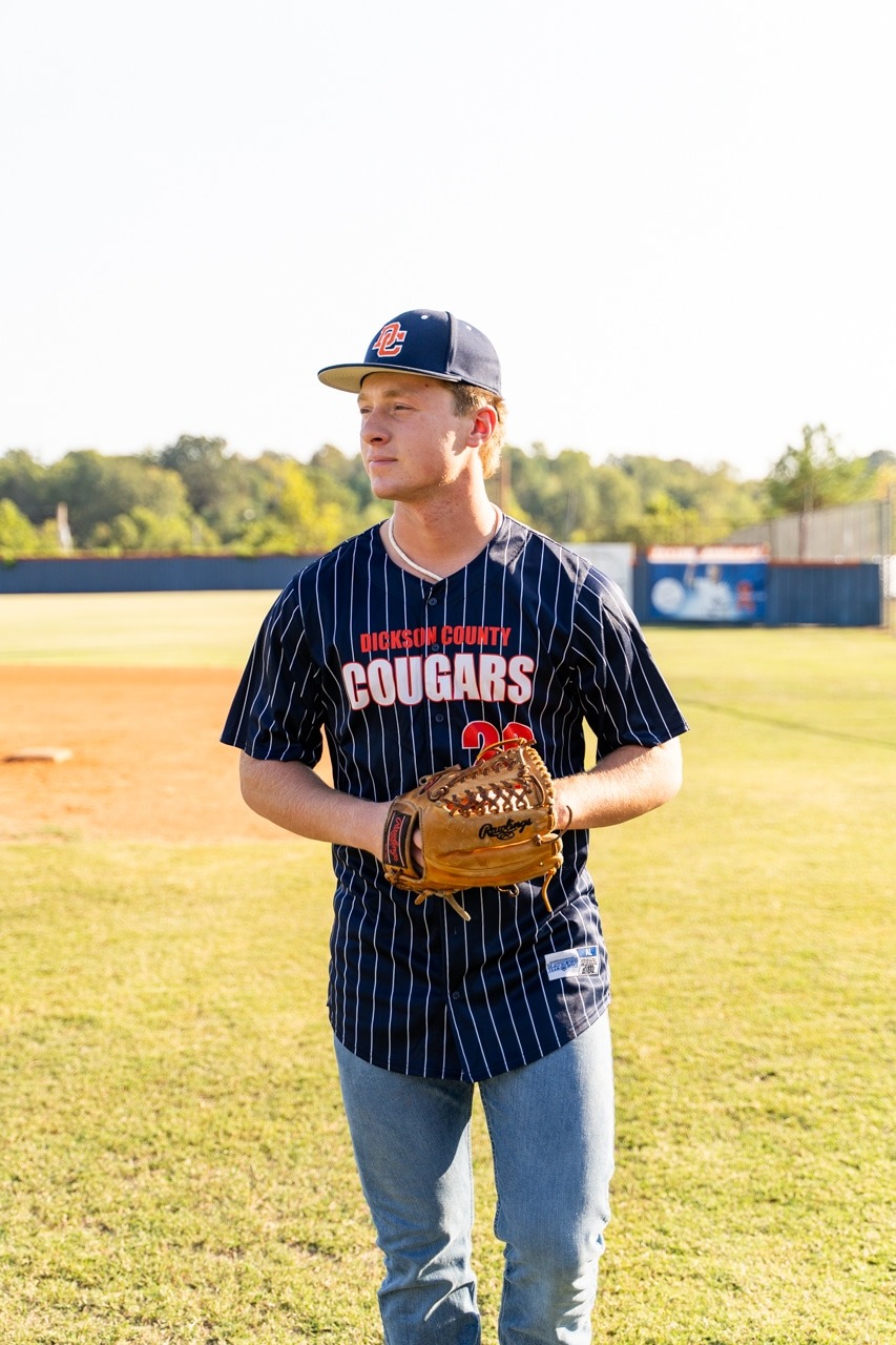 High School senior posing in baseball uniform on field<br />
